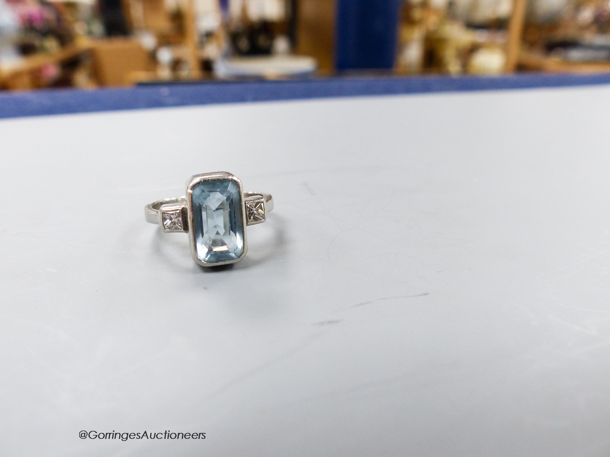 A modern platinum, aquamarine and diamond set three stone dress ring, size N, gross weight 6.8 grams.